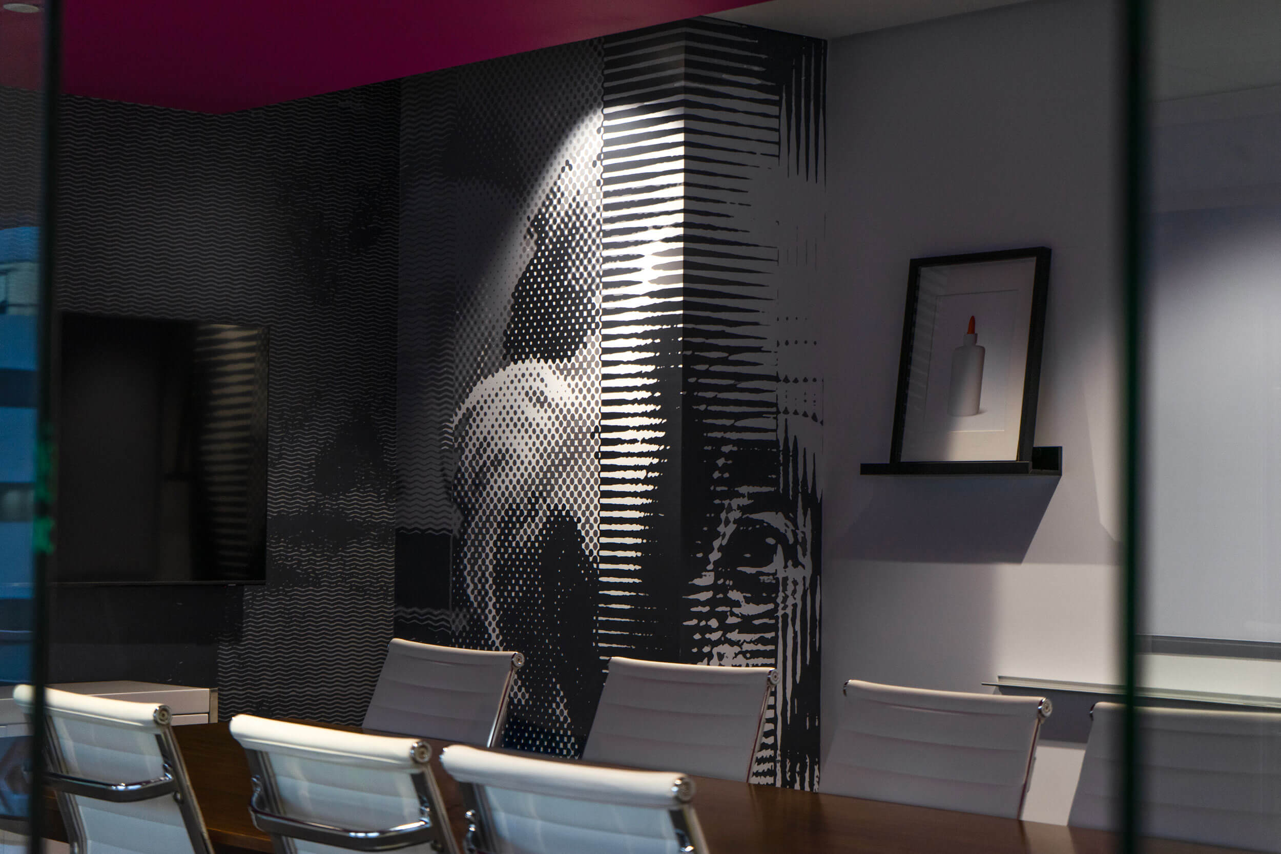Conference room at GlueIQ headquarters — halftone wall mural and a framed print of a glue bottle