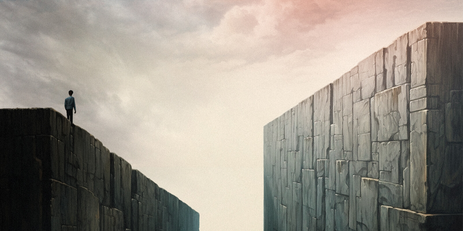 Lone figure standing on a stone wall, facing the gap to a taller wall ahead